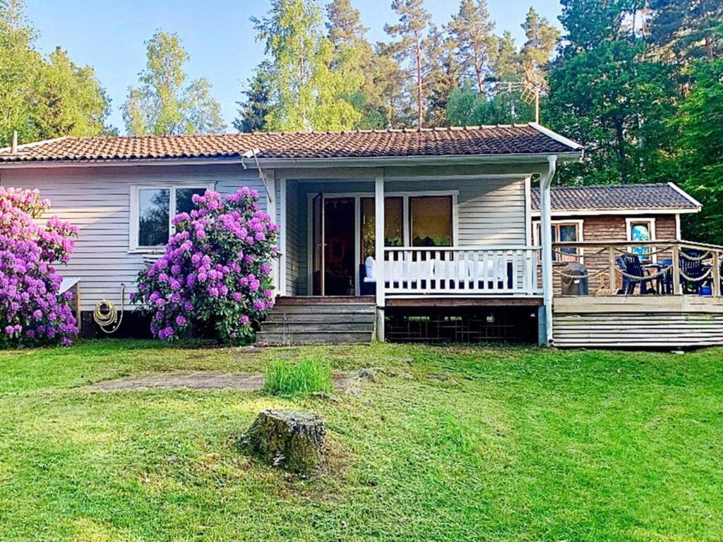 a small house with a porch and flowers in the yard at Holiday home Backaryd II in Backaryd