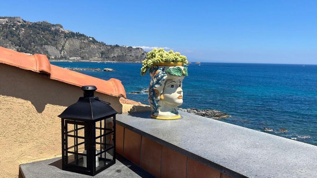 a vase with a head on a wall next to the ocean at SEA VIEW Apartment in Giardini Naxos