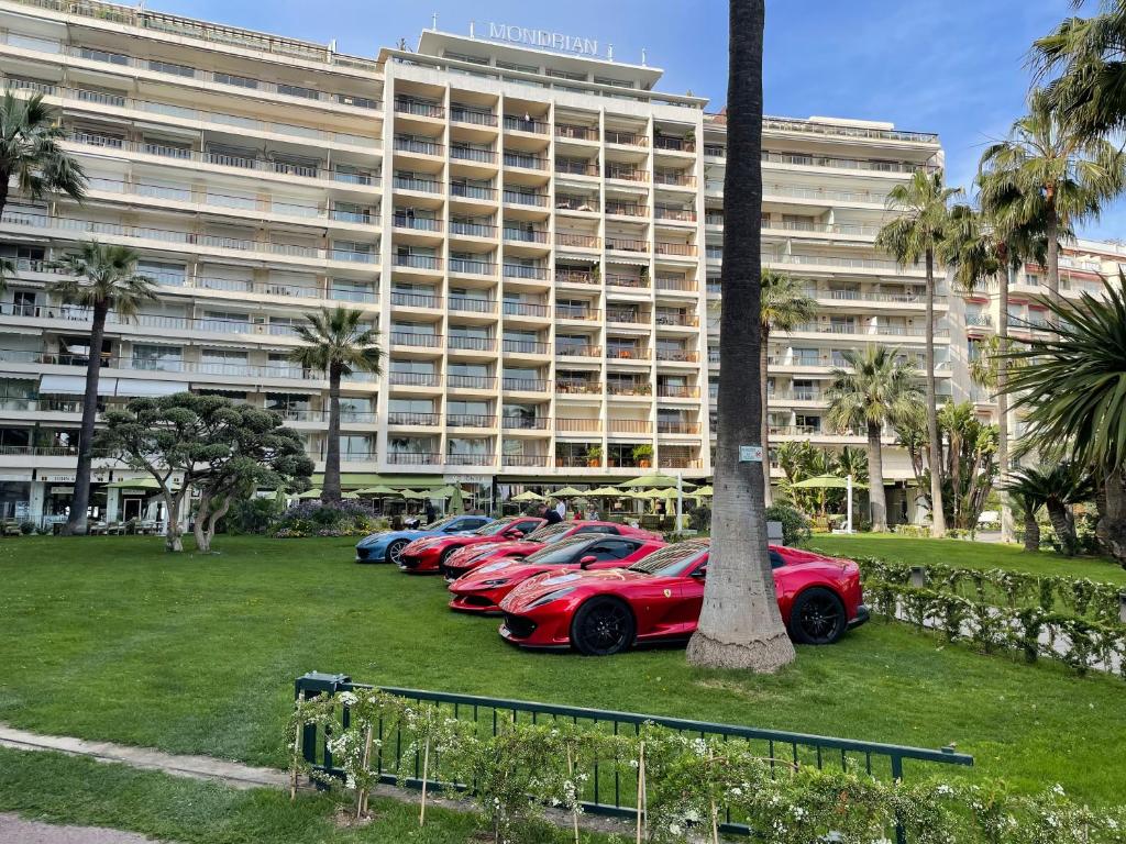 une rangée de voitures garées devant un grand bâtiment dans l'établissement Ibis croisette, à Cannes