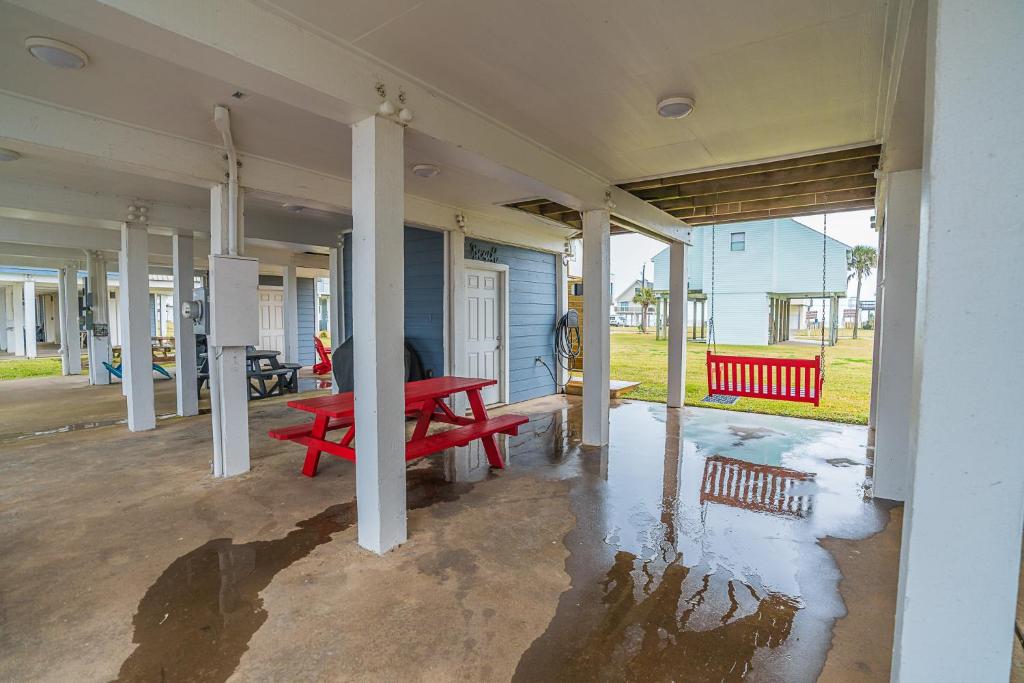 a red bench sitting on the porch of a house at Hot Tub - Ocean Views - Steps to Private Beach - Quiet Location in Galveston