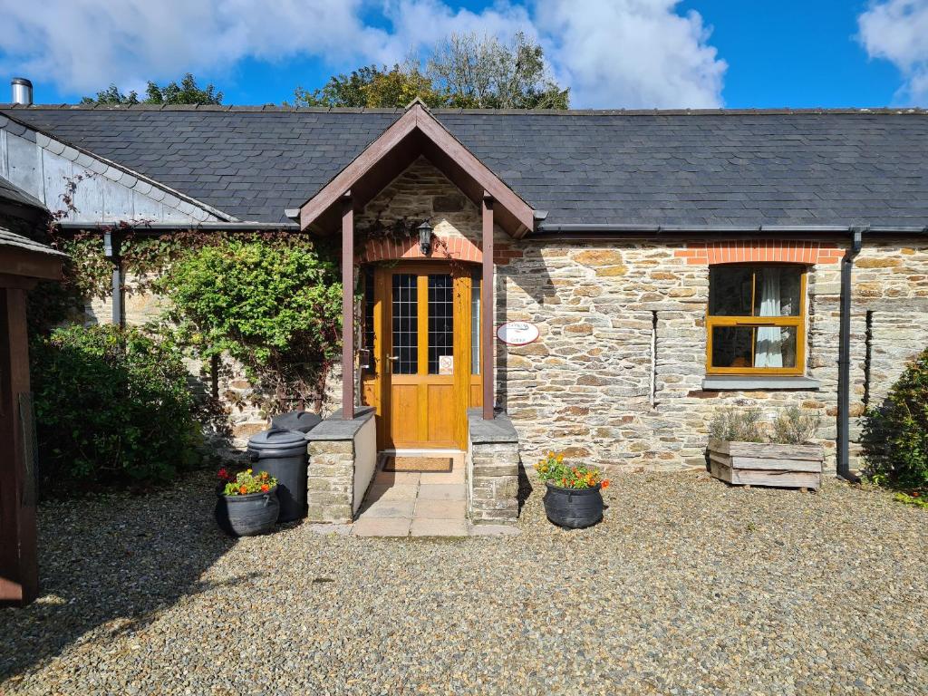 a stone cottage with a wooden door and flowers at Sandpiper Cottage in Llanboidy