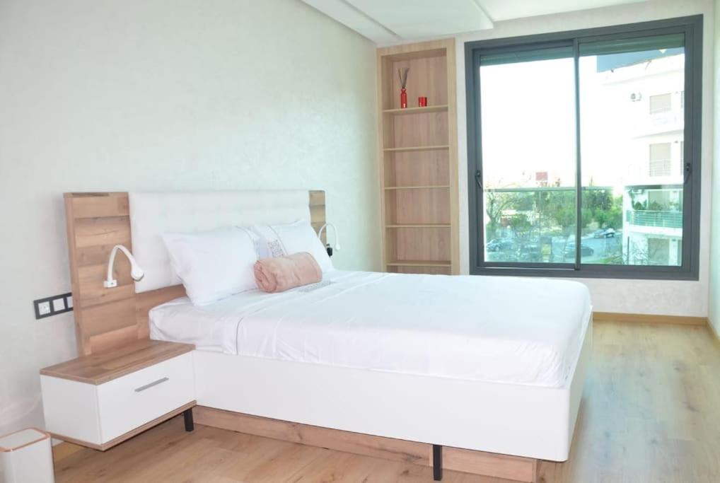 Un dormitorio blanco con una cama grande y una ventana en Appartement FES Hayat Luxury, en Fez