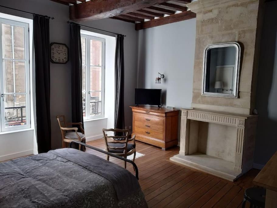 1 dormitorio con 1 cama, chimenea y TV en Authentique studio au cœur de Bayeux en Bayeux