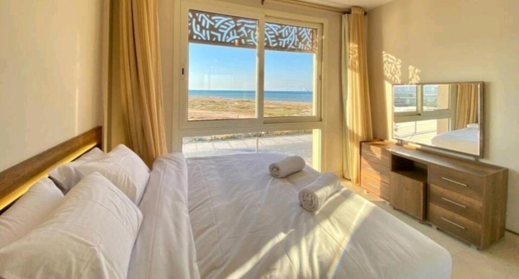 - une chambre avec un grand lit blanc et une fenêtre dans l'établissement Mangroovy El Gouna Full SEA View 1 BR, El Gouna, à Hurghada