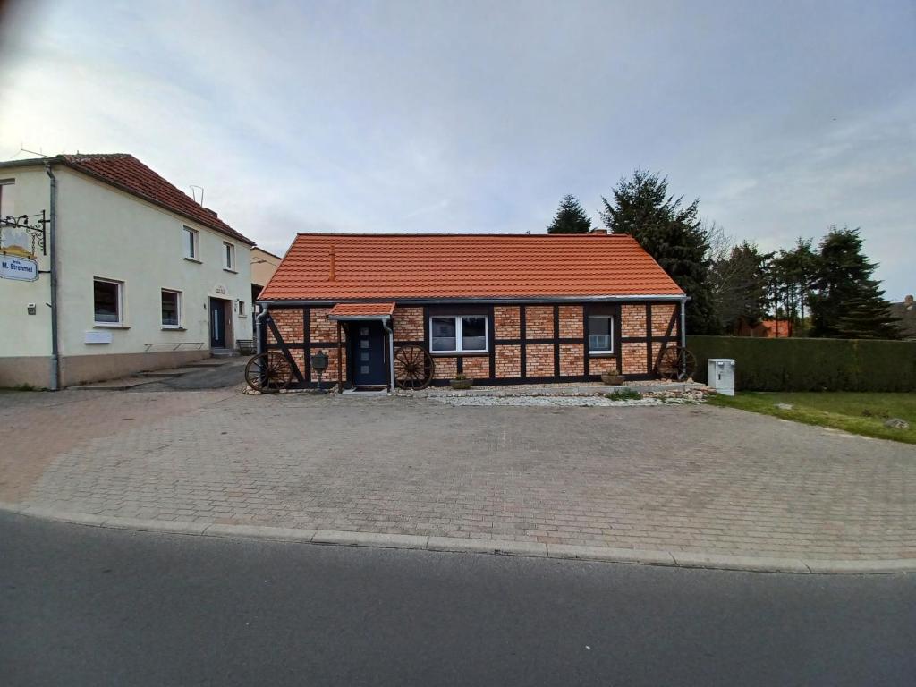 een huis met een oranje dak op een straat bij Zum alten Schmied Vermietung und Verpachtung Schönfeld 