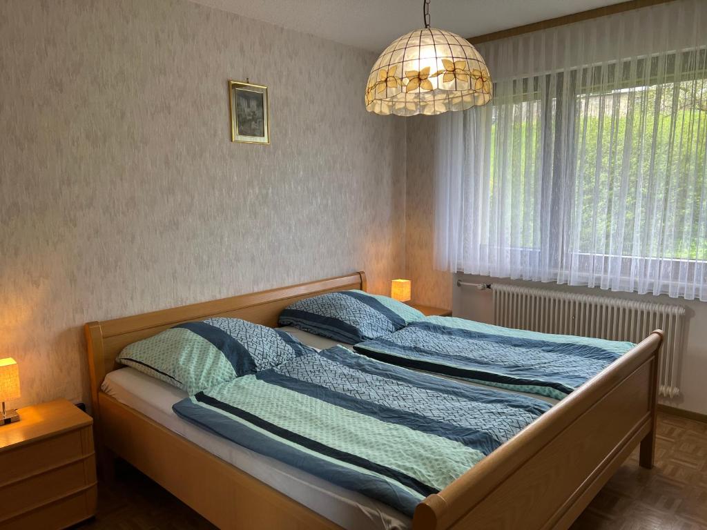 a bedroom with a bed with blue sheets and a chandelier at Doppelzimmer Nr 4 in Freiensteinau