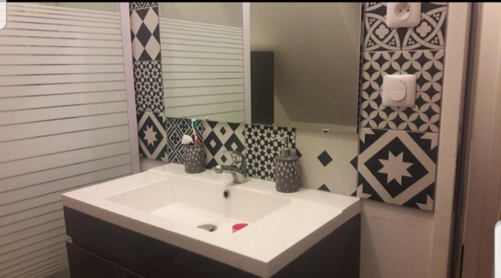 ein Badezimmer mit einem weißen Waschbecken und einem Spiegel in der Unterkunft Chambre proche circuit 500 m du virage de Mulsanne in Mulsanne