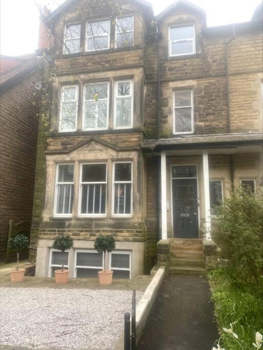 an old brick house with two potted plants in front of it at Dragon Parade Apartment in Harrogate