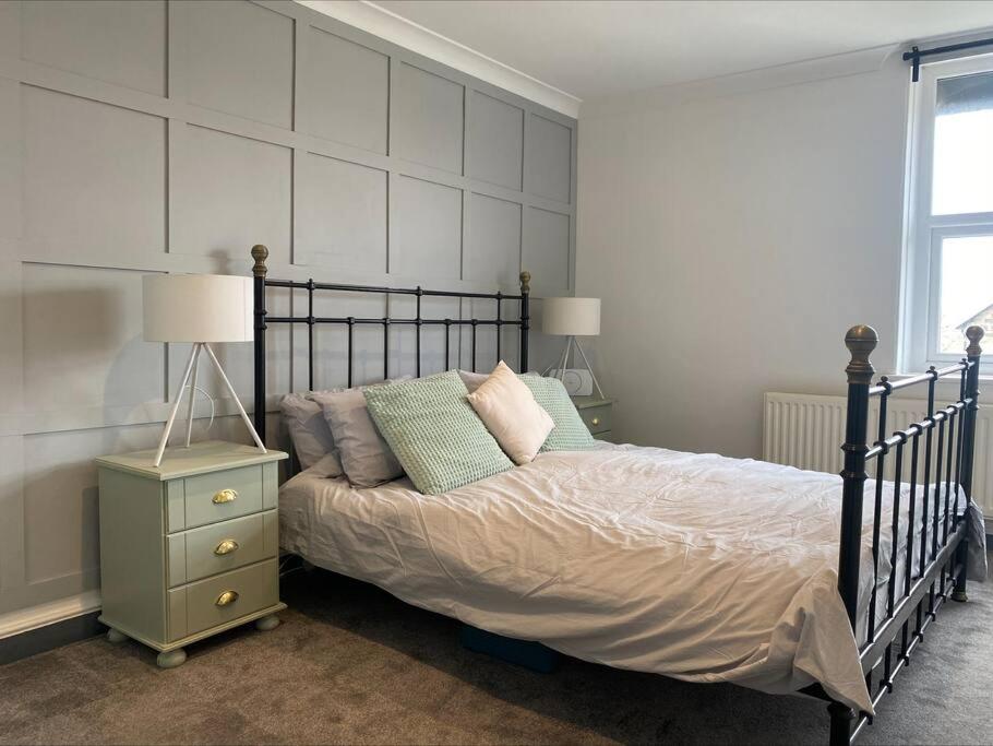 a bedroom with a bed with pillows and a night stand at Dragon Parade Apartment in Harrogate