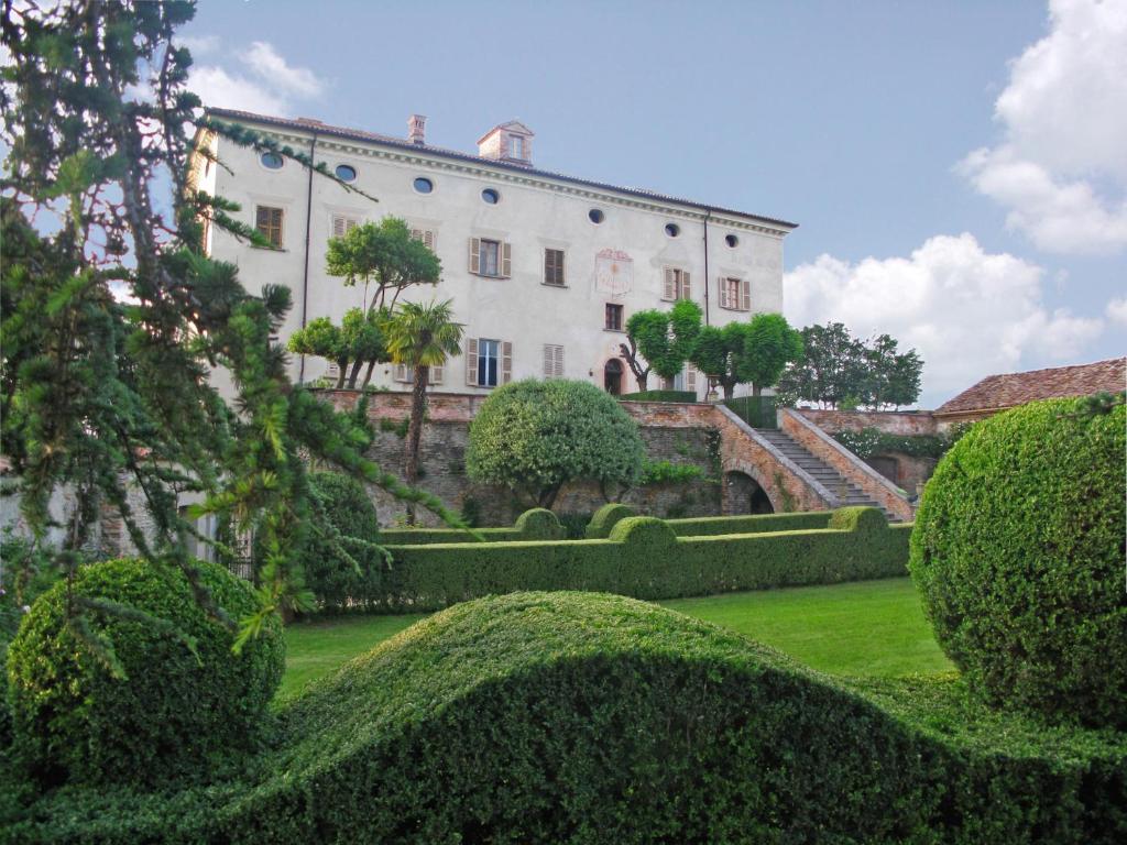 een groot wit gebouw met struiken ervoor bij Castello di Coazzolo in Neive