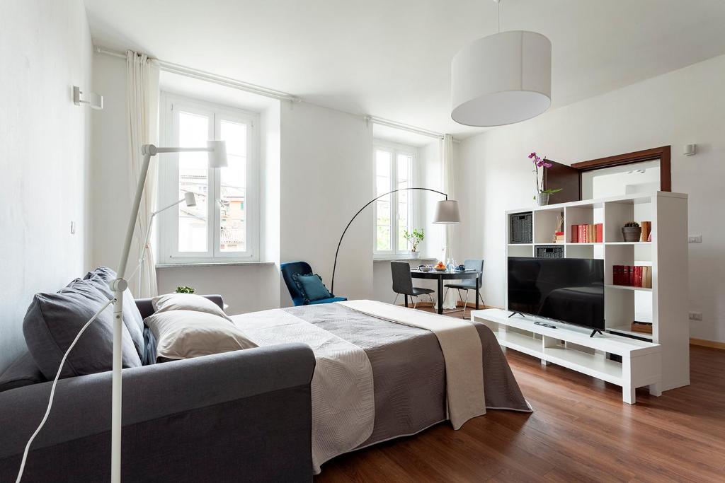 a white bedroom with a bed and a television at A central quiet sunny studio in Verbania in Verbania