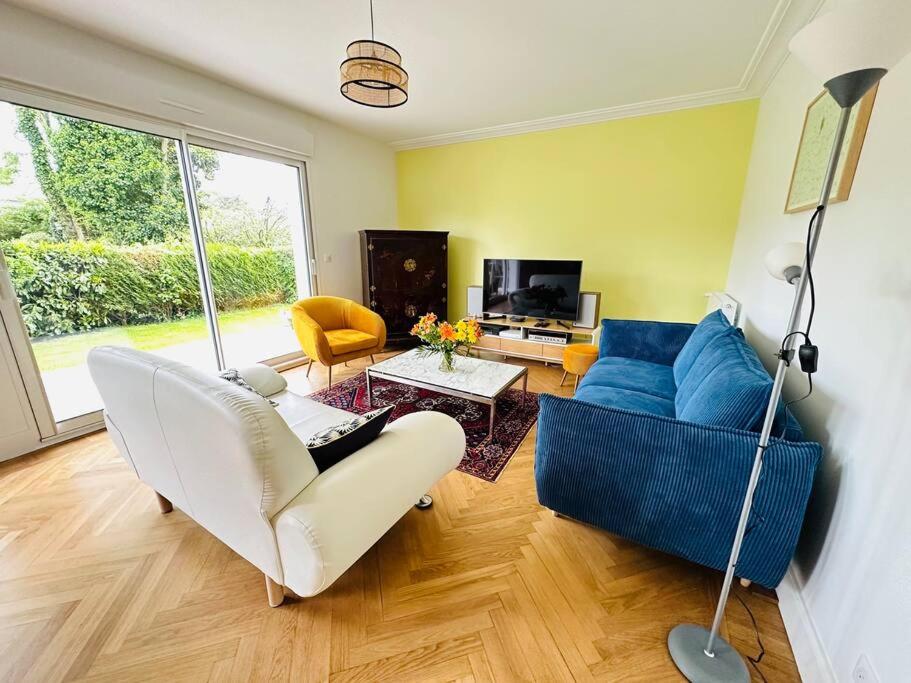 un salon avec un canapé bleu et une télévision dans l'établissement Maison d’architecte - plages, à Larmor-Plage