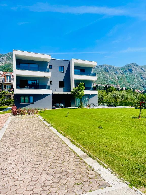 a large white building with a green lawn in front of it at Villa Barovic - Premium apartment in Mlini