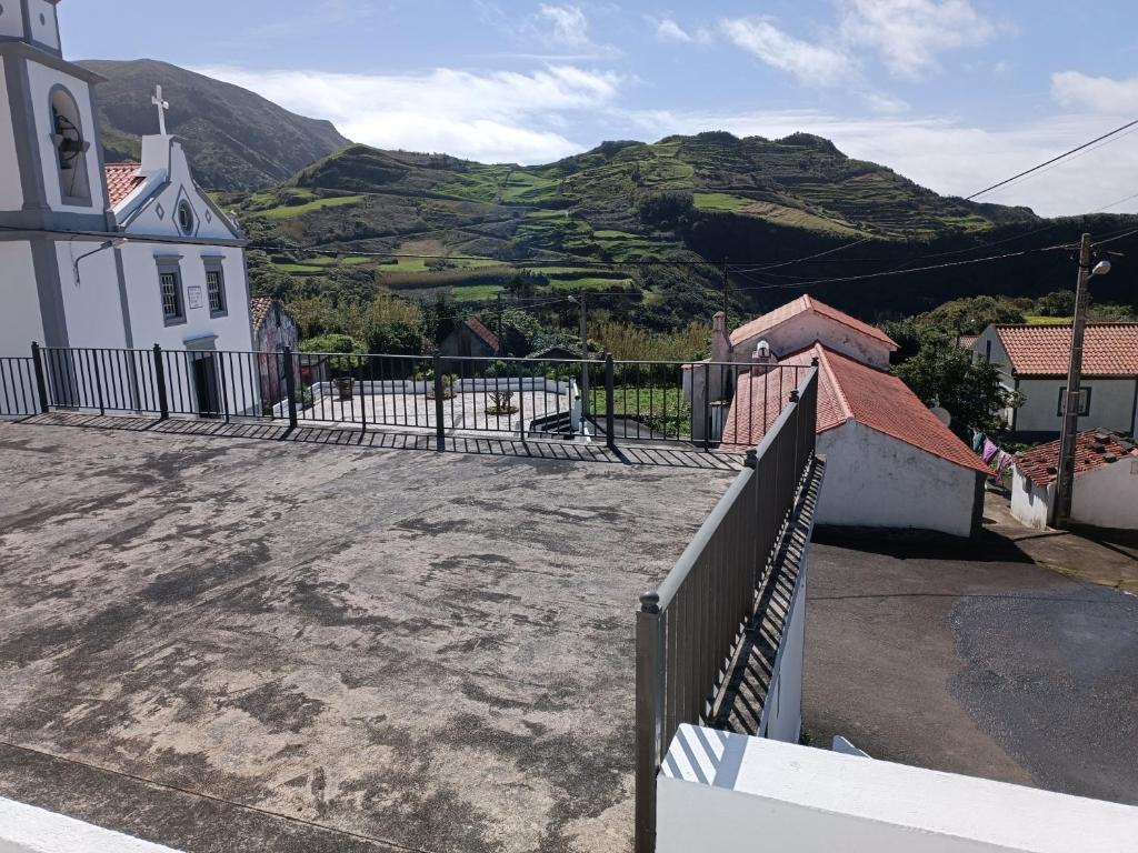 a church with a fence in front of a mountain at Alojamento Local M&I in Lajes das Flores