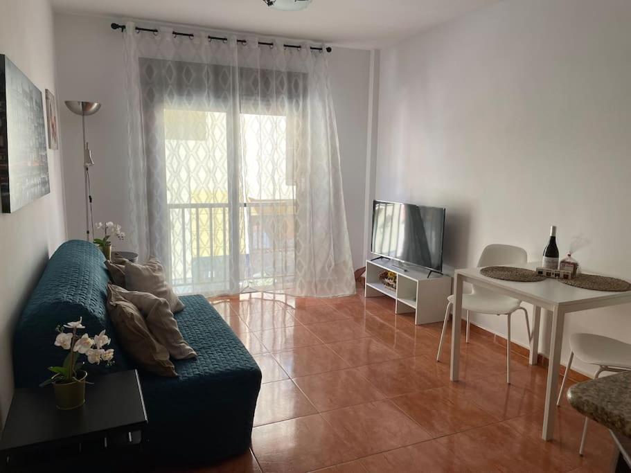 a living room with a couch and a table and a tv at Acogedor apartamento en Playa De Santiago in Alajeró