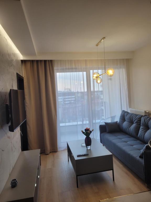 a living room with a blue couch and a table at Apartament Centrum Pestige Mińsk in Mińsk Mazowiecki