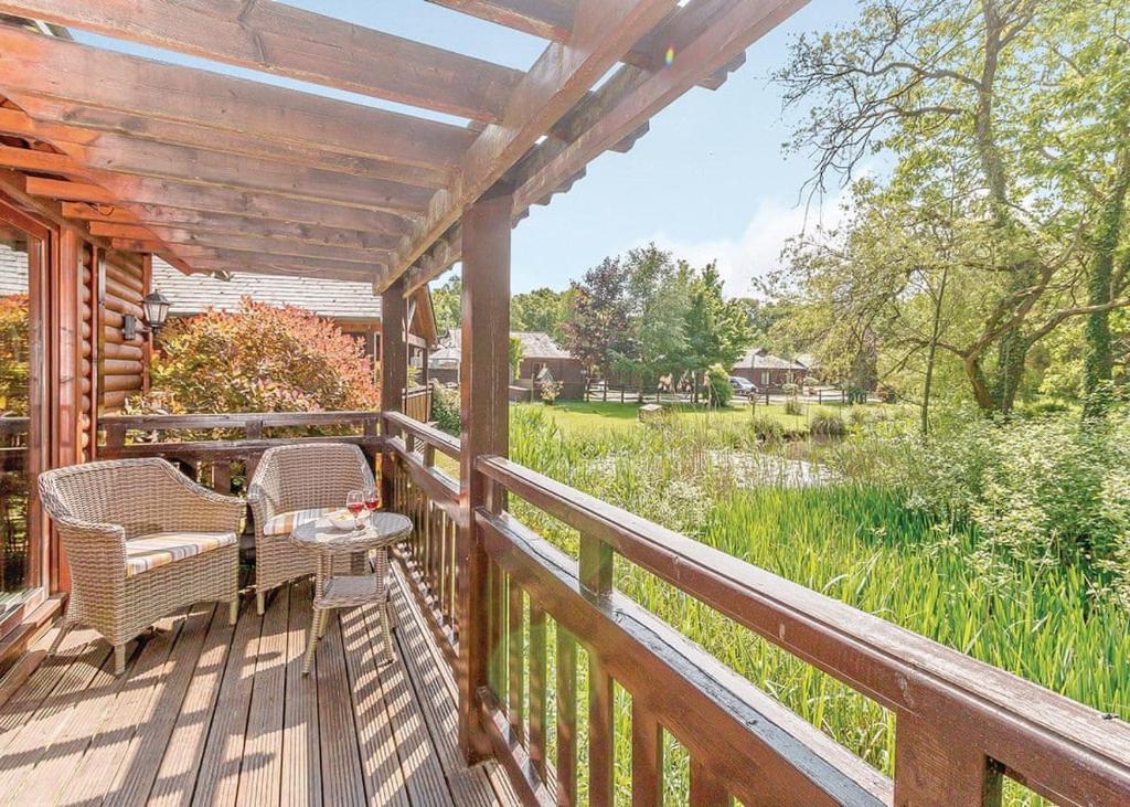 a porch with chairs and a table and a view of a field at Tilford Woods Lodge Retreat in Farnham