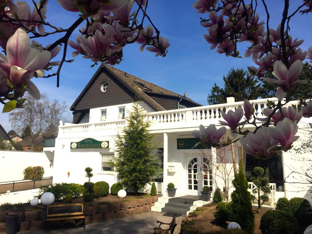 a white building with magnolia trees in front of it at Hotel Ramor Garni in Duisburg