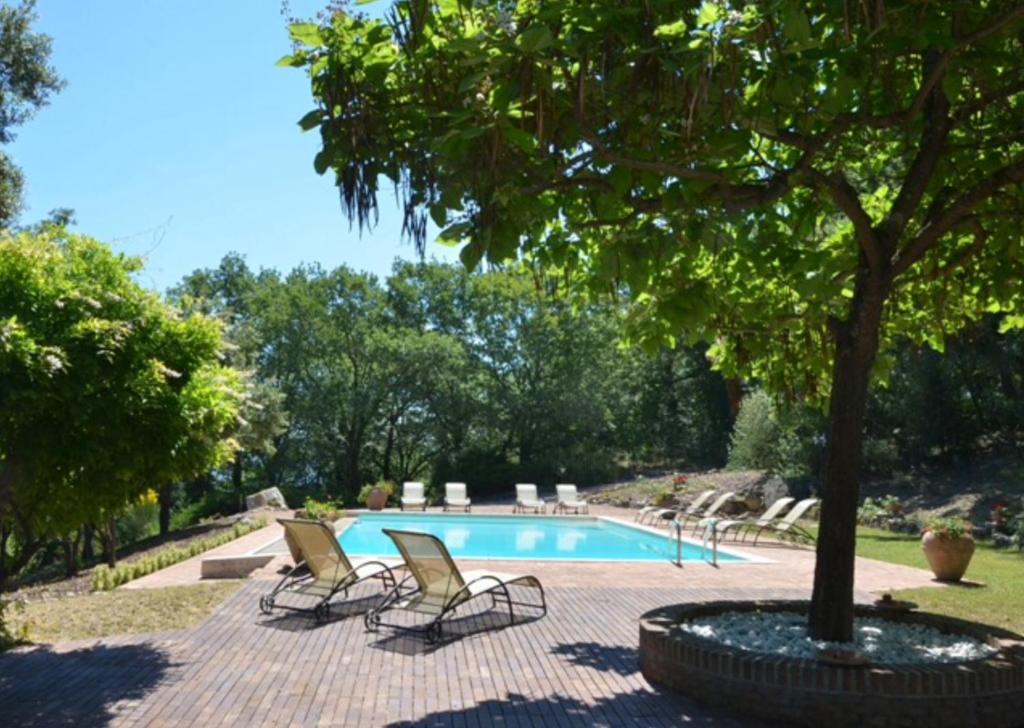una piscina con due sedie a sdraio e un albero di San Valentino Castle near Todi ad Acqualoreto