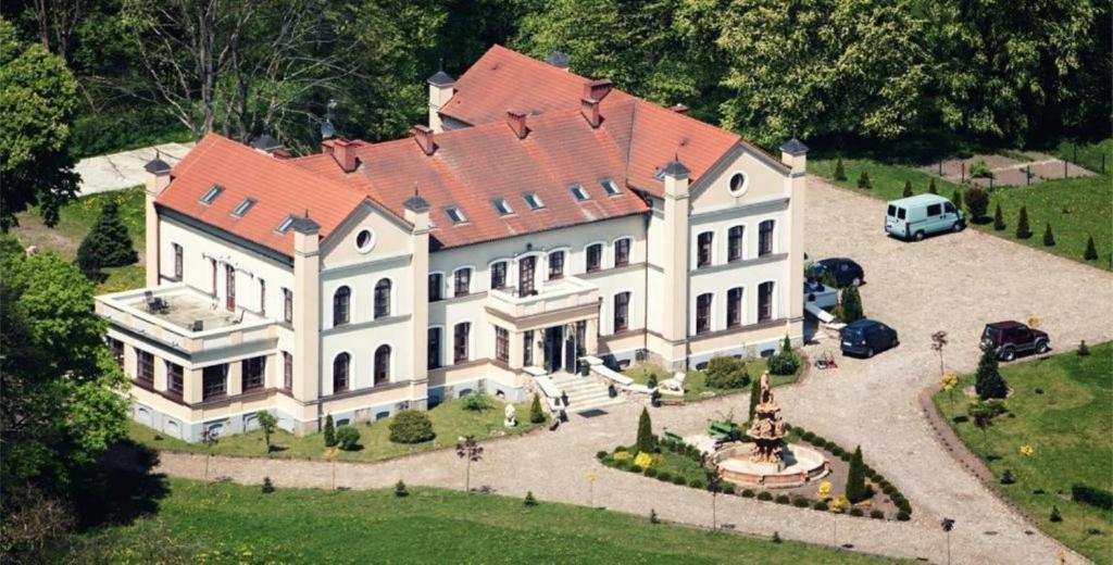 una gran casa blanca con techo rojo en Pałac SŁONOWICE, en Brzeżno