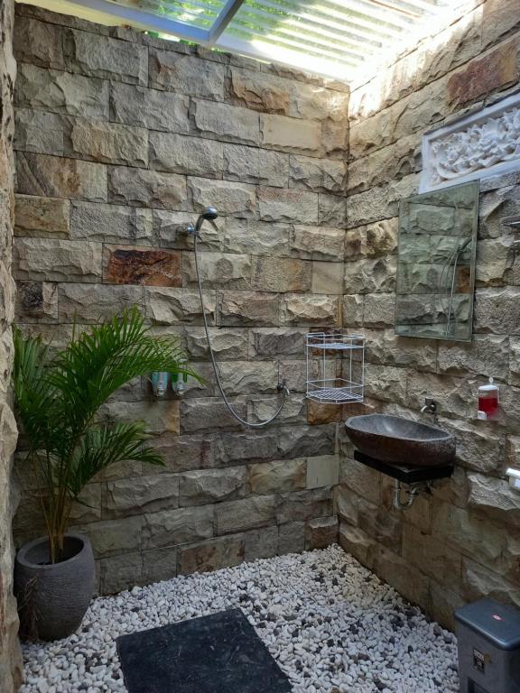 a stone bathroom with a sink and a plant at Kubu Kawi in Munduk