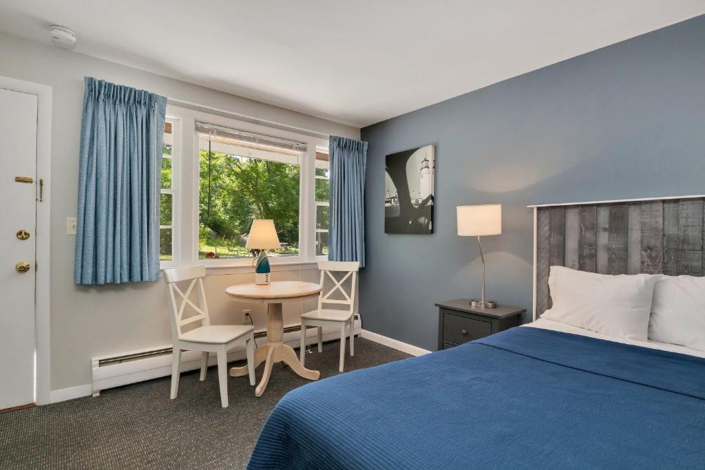 um quarto com uma cama azul, uma mesa e cadeiras em Handkerchief Shoals Inn em Harwich