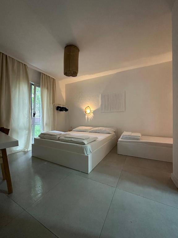 a white bedroom with two beds and a window at Villa Vele in Herceg-Novi