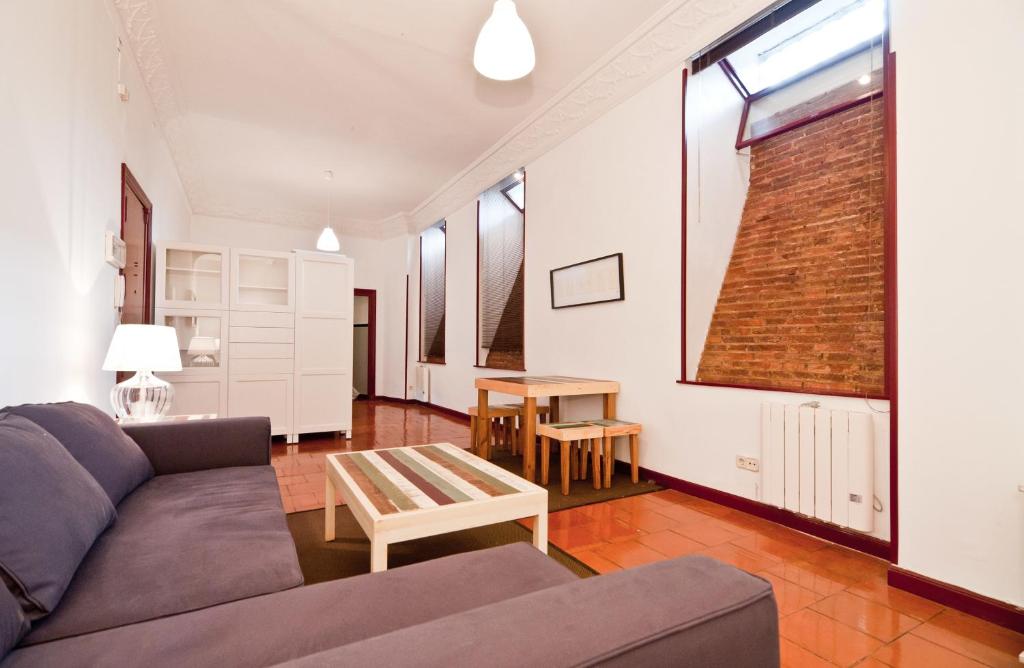 ein Wohnzimmer mit einem Sofa und einem Tisch in der Unterkunft Apartamentos Madrid Retiro in Madrid