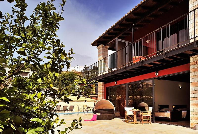 a house with a patio with a table and a balcony at Ornella Beach Resort & Villas in Syvota