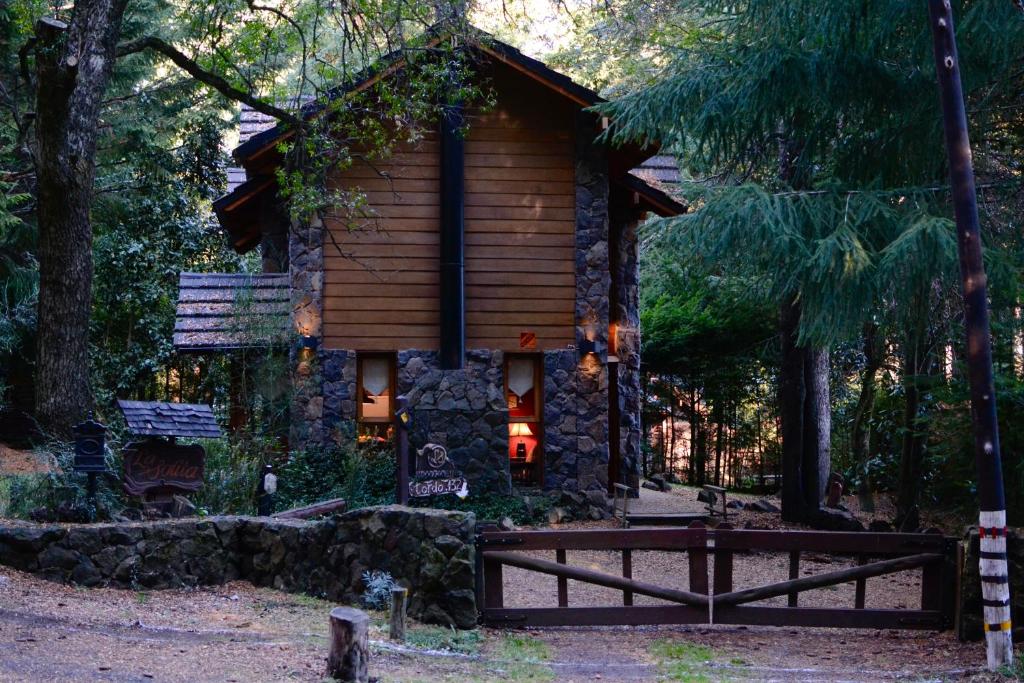 una cabaña de madera en el bosque con un banco delante en La Solita en Villa La Angostura