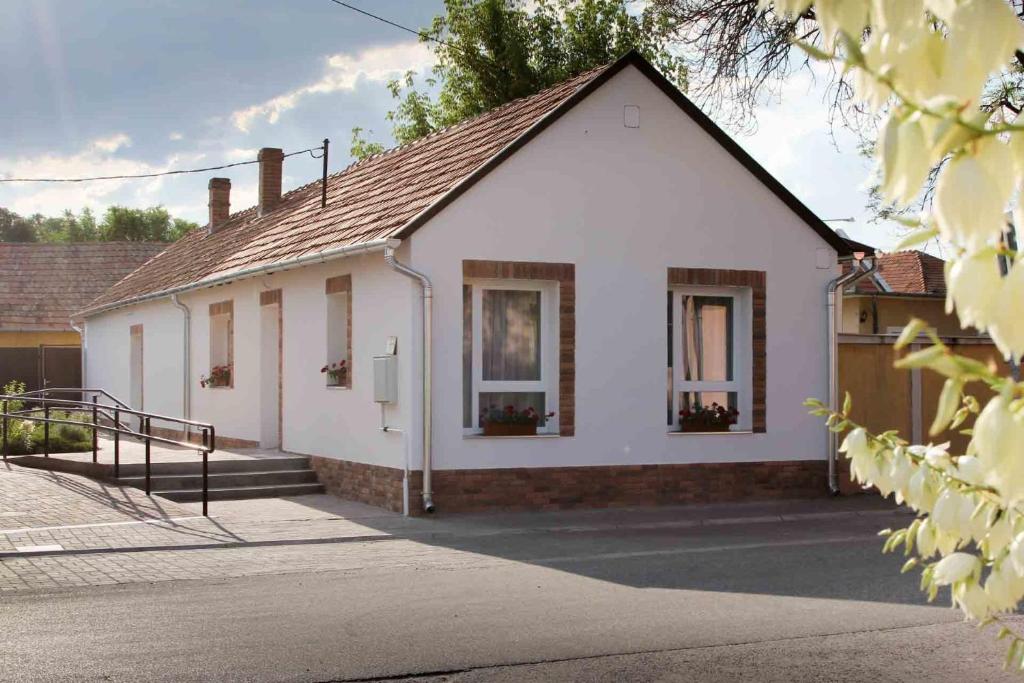 a white house with windows and a driveway at Írisz Apartmanház in Mórahalom