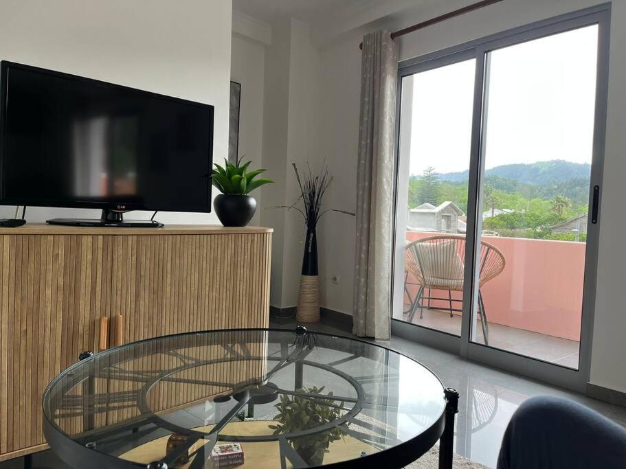 een woonkamer met een glazen tafel en een televisie bij Natural Living Vacations in Furnas