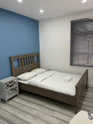 um quarto com uma cama grande e uma parede azul em EAST LONDON APARTMENTS SELF check in em Londres