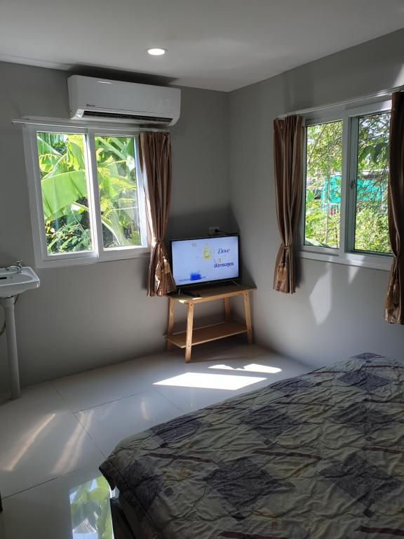 - une chambre avec un lit, une télévision et des fenêtres dans l'établissement Nature Home, à Phra Nakhon Si Ayutthaya
