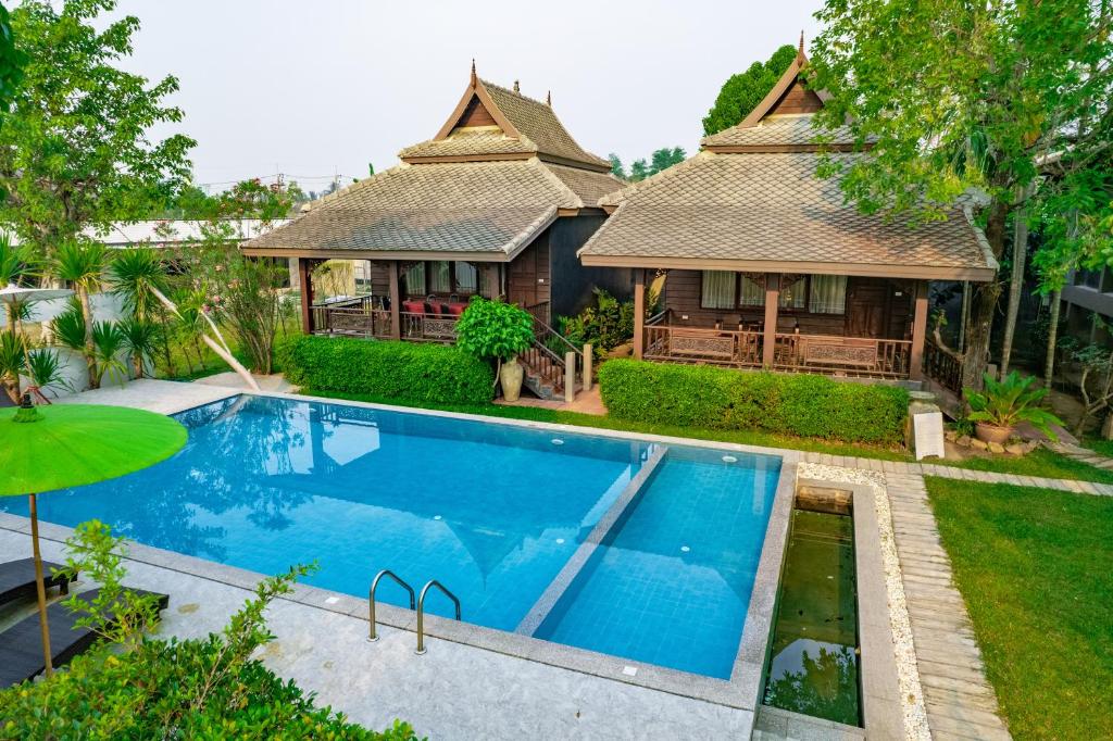 une villa avec une piscine en face d'une maison dans l'établissement มนต์เมืองเชียงใหม่ รีสอร์ต Monmuang Chiangmai Resort, à Hang Dong