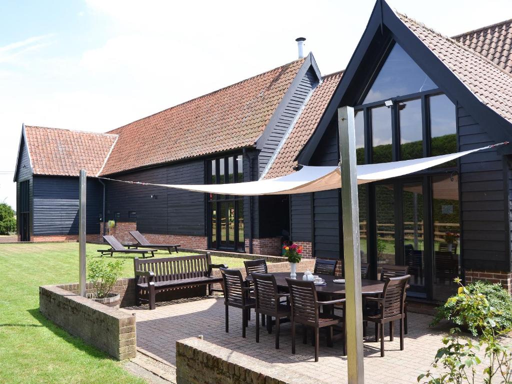 a patio with a table and chairs and a building at Clamp Farm Barn in Stowmarket
