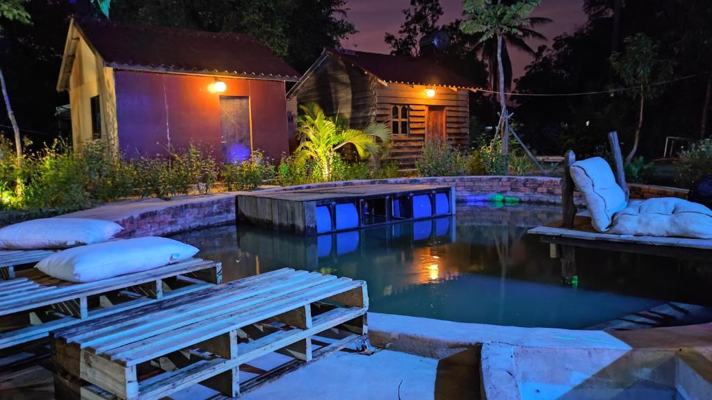 a pool in a backyard at night with lights at The Bear Bungalow in Kampot