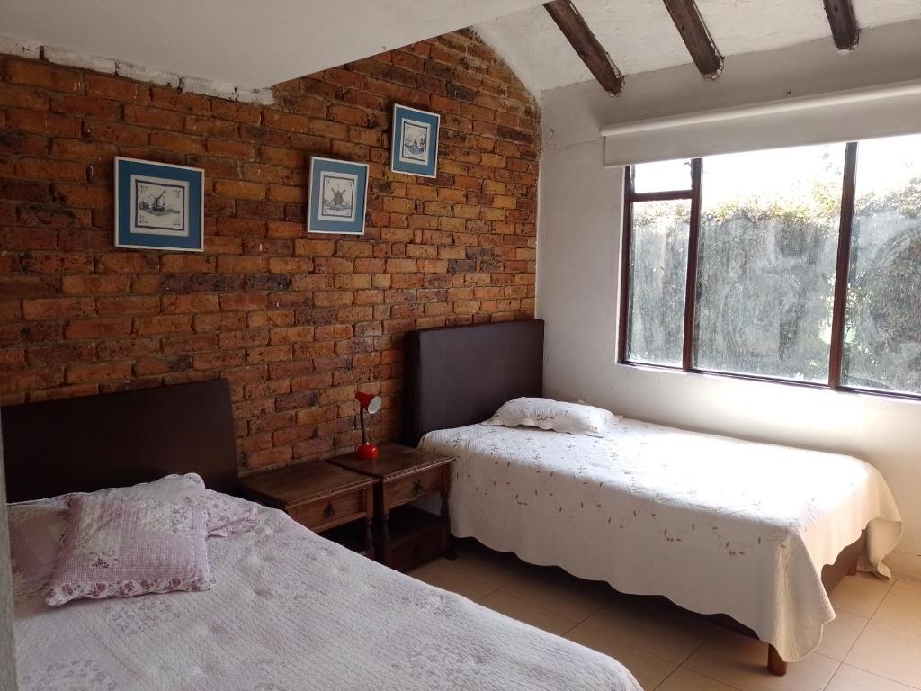 sypialnia z 2 łóżkami i ceglaną ścianą w obiekcie Encantadora Finca San Gabriel Duitama w mieście Duitama