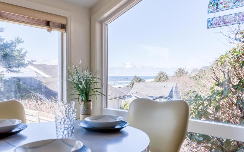 une salle à manger avec une table, des chaises et une grande fenêtre dans l'établissement Birds Eye Beach House, à Lincoln City