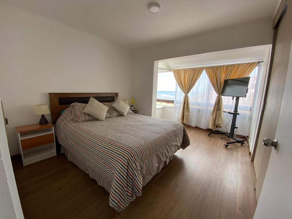 um quarto com uma cama e uma grande janela em Departamento con vista al mar em Viña del Mar
