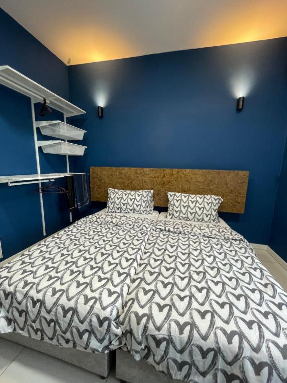 a bedroom with a large bed with a blue wall at jugi suite @ Horizon Sepang KLIA in Sepang
