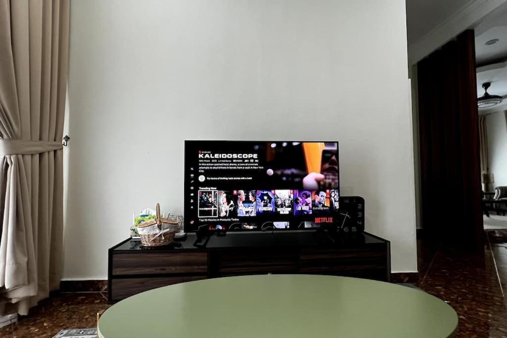 a living room with a flat screen tv and a table at Kamilia Homestay KB City Centre in Kota Bharu