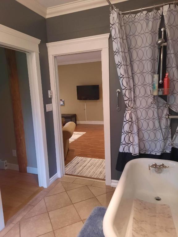 a bathroom with a tub and a room with a tv at Beaver Hut Bed And Breakfast in Port Alberni