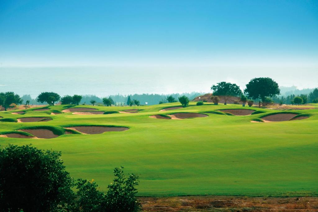 a view of a golf course with green grass at Capital Coast Resort And Spa in Paphos