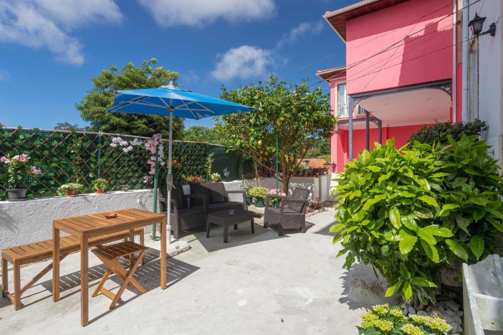 eine Terrasse mit einem Holztisch und einem Sonnenschirm in der Unterkunft Happy Holiday Sintra in Sintra