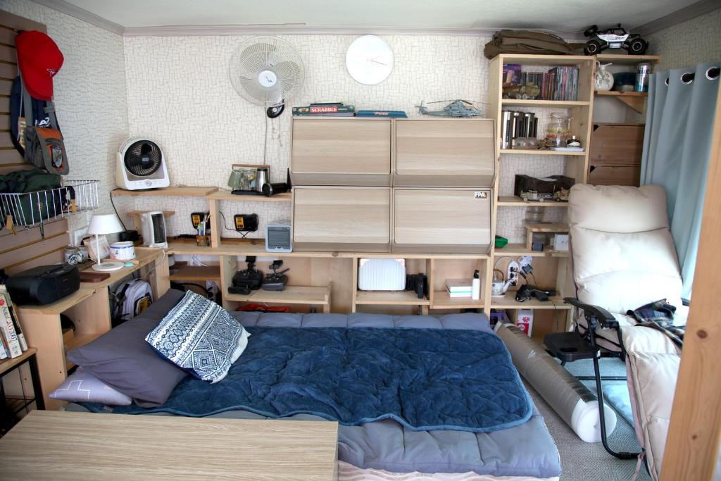 a bedroom with a bed and a desk and shelves at Camp k in Mokpo