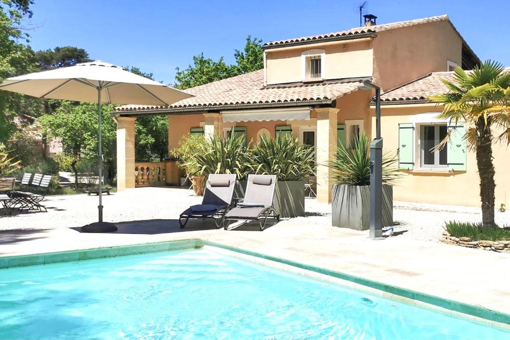 ein Haus mit einem Pool mit zwei Stühlen und einem Sonnenschirm in der Unterkunft LA VILLA DU PETIT BOIS Les Lavandes in Faucon