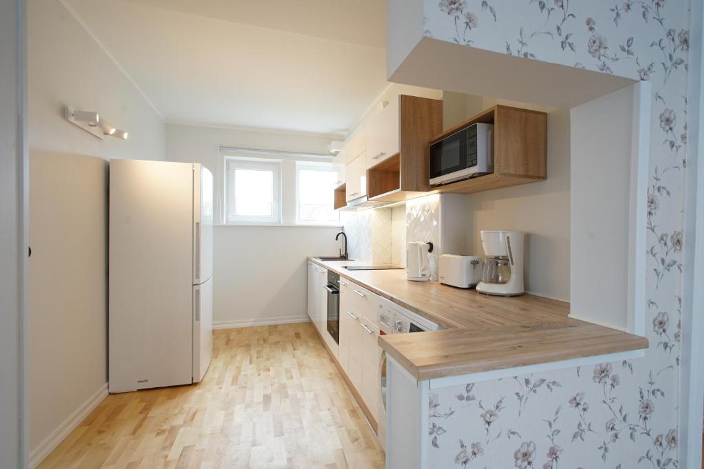 a kitchen with a white refrigerator and wooden cabinets at Papli Beach Apartment in Pärnu