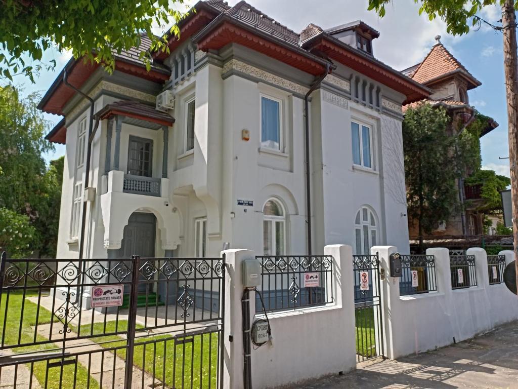 a white house with a fence in front of it at Villa Maria De Luxe in Bucharest