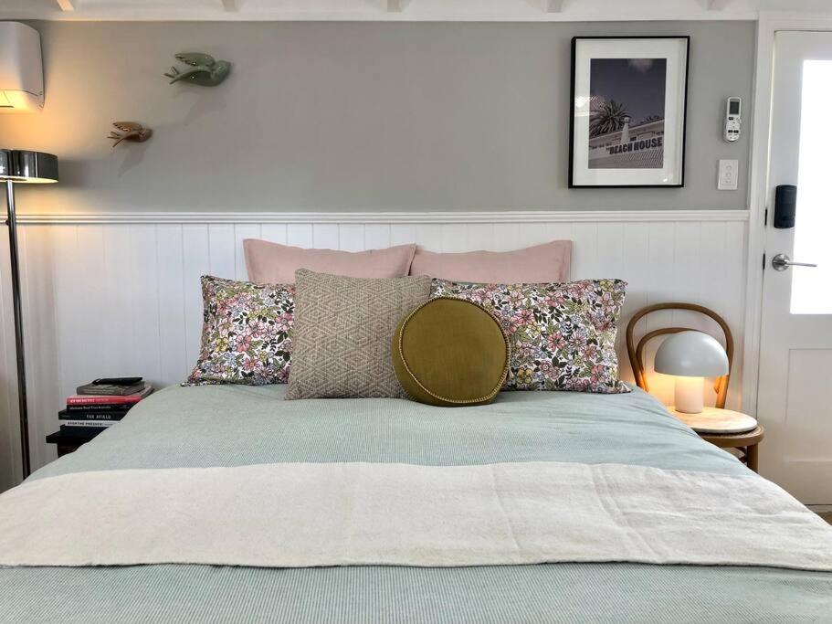 a bedroom with a bed with pink and gray pillows at Limeburners Loft Geelong - Walk to CBD Waterfront Hospitals in Thomson